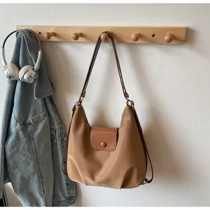 Detail of camel brown leather tote bag with silver buckle hanging on a wooden rack