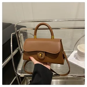 Detail of vintage brown leather crossbody bag with wave flap and gold twist lock