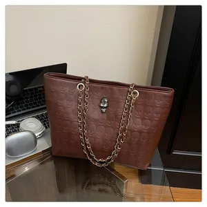Détail du sac cabas en cuir marron à motifs tête de mort et bandoulière en chaîne