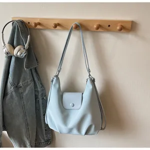 Detail of light blue shoulder bag with button flap closure and side zipper design