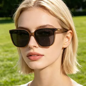 Close-up of square oversized sunglasses with brown frame and golden wing emblem on temple