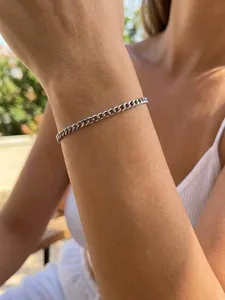 Primo piano di un bracciale a catena cubana argento su un polso di una donna