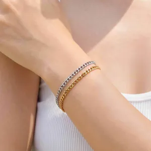 Bracciali minimalisti a catena cubana oro e argento indossati sotto la luce naturale