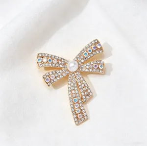 Macro shot of bow brooch with gold plating, colorful rhinestones and central white pearl