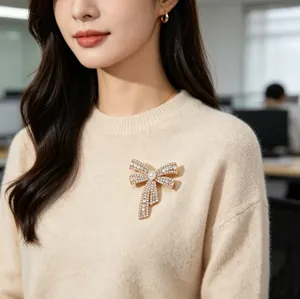 Elegant gold bow brooch with sparkling crystals and a central pearl on a classic blazer