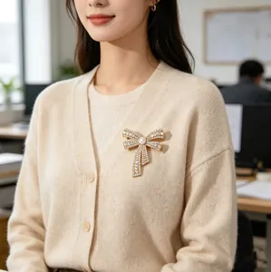 Close-up of bowknot brooch with pearls and crystals on a beige knitted cardigan