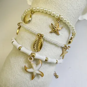 Detail of three-piece ocean charm bracelets featuring starfish and shells on white fur