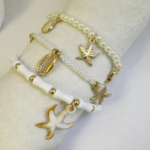 Detail of bohemian beaded anklet set with golden starfish and shell charms on a display stand