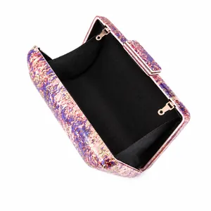 Detail view of colorful acrylic shell evening bag with golden metal frame and chain hooks