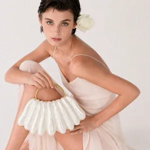 Elegant white wavy acrylic evening clutch with gold circular handle and pearl finish