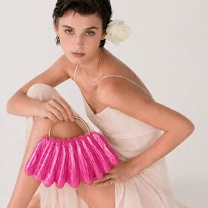 Detail view of the rose pink shell-shaped evening clutch with gold metal ring handle