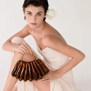 Professional model showcasing a brown wavy acrylic evening clutch bag for formal events