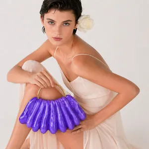 Detail of purple wavy acrylic evening clutch featuring a gold circular metal handle