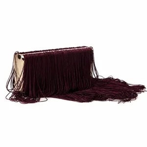 Détail de longues franges en soie bordeaux sur pochette de soirée avec cadre doré