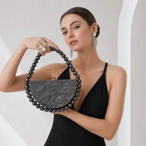 Detail of a black marble texture evening clutch with large glossy beaded handle
