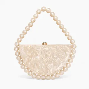 Detail of pearlescent marble acrylic evening bag with elegant large pearl handle clasp