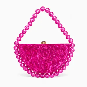 Macro shot of rose red acrylic evening bag with marble texture and beaded handle