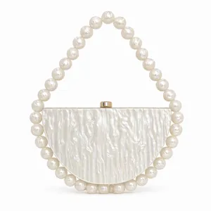 Detail of pearlescent acrylic evening bag with large pearl handle and gold clasp