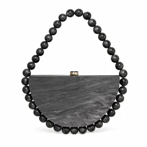 Detail of crescent acrylic evening bag with grey marble texture and beaded handle