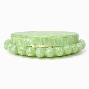 Close-up of light green marble acrylic evening bag with bead trim and gold hinges