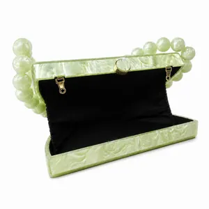 Detailed interior of light green acrylic clutch with marble texture and bead handle