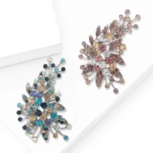 Elegant irregular crystal brooches in blue and pink tones on white geometric podium