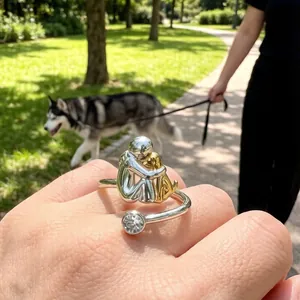 Detail of two-tone open ring featuring a person hugging a dog with a sparkling zircon