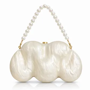 Macro view of shell texture acrylic clutch bag with pearl handle and gold clasp hardware