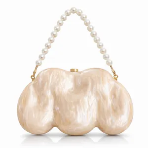Detail of shell-shaped acrylic clutch with marble texture and large pearl handle