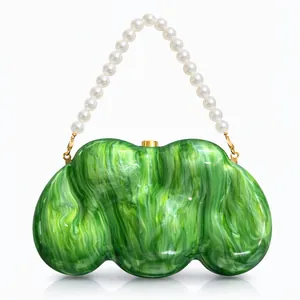 Close-up of emerald green marbled acrylic clutch with elegant white pearl handle