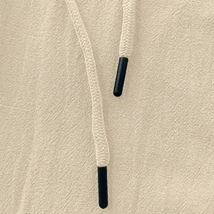 Close-up of linen trousers featuring beige woven texture and drawstring detail