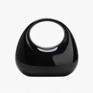 Polished black oval handbag with integrated circular top handle and reflective finish