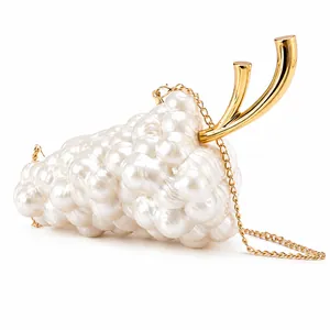 Detail view of grape-shaped evening bag with white pearls and gold metal stem handle