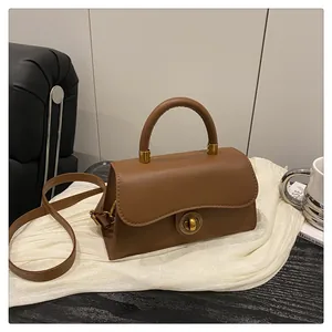 Close-up of vintage gold clasp on brown leather handbag with adjustable strap
