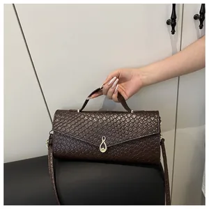 Détail d'un sac à main marron foncé tressé avec boucle métallique dorée infini