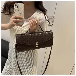 Détail d'un sac à main marron foncé à texture tressée et fermoir doré chic