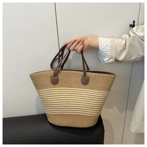 Detail of hand-woven straw tote with contrast stripes and brown leather handles