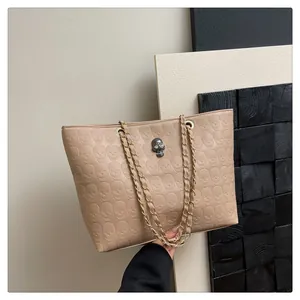 Vue détaillée du sac cabas beige avec motif tête de mort en relief et chaîne dorée