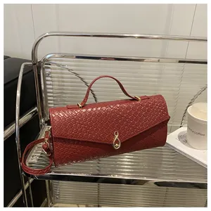Détail d'un sac à main rouge foncé à texture tressée avec boucle dorée et bandoulière
