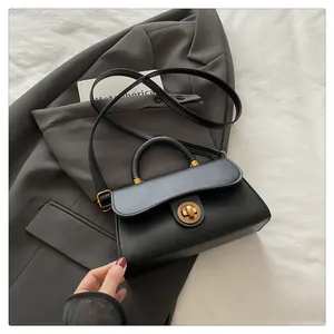 Detail of classic black handbag with golden swivel lock on professional grey blazer