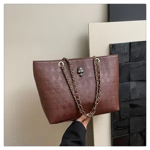 Détail du cabas marron avec motifs de crânes en relief et bandoulière en chaîne