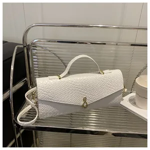 Gros plan sur la texture tressée et le fermoir doré du petit sac à main blanc élégant
