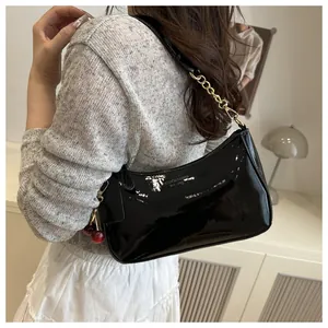 Sac à épaule en cuir verni noir brillant avec chaîne dorée et breloque cerise rouge