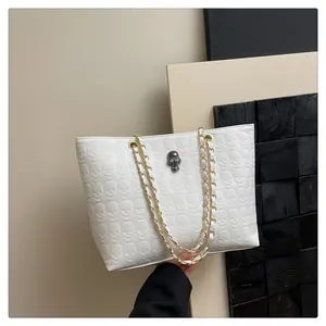 Détail du sac cabas blanc avec motifs crâne en relief et bandoulière chaîne dorée
