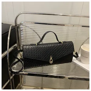Détail d'un sac à main tissé noir avec fermoir doré de luxe sur un support argenté