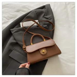 Brown vintage handbag with gold clasp detail on a grey suit and white fabric