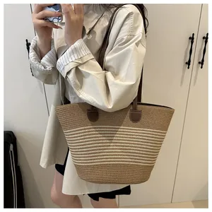 Close-up of a woven straw tote bag with cream stripes and brown leather strap details