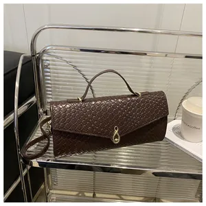 Détail du sac à main marron foncé tressé avec fermoir doré sur étagère moderne