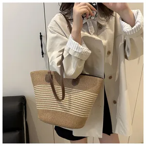 Detailed close-up of brown leather handles and striped woven texture on a large straw tote bag