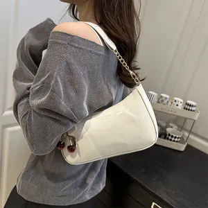 Sac à bandoulière en cuir brillant blanc avec pendentif cerise et chaîne dorée